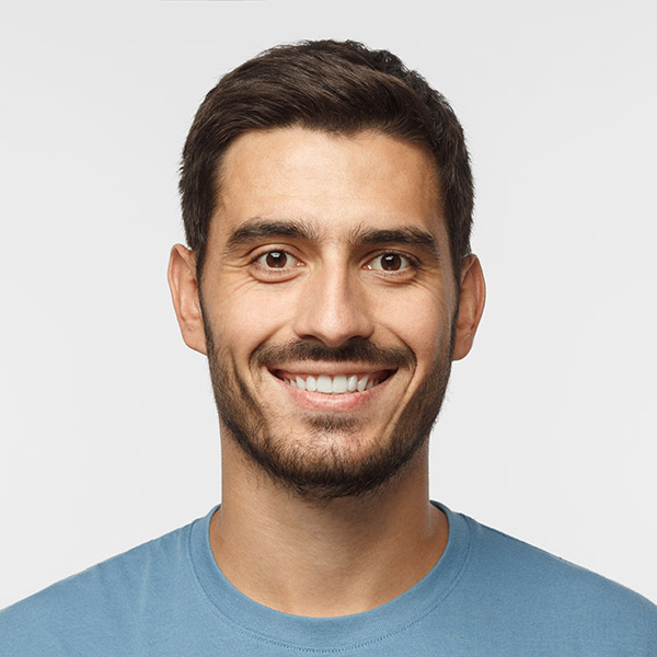 Close up portrait of young smiling handsome guy in blue t-shirt isolated on gray background